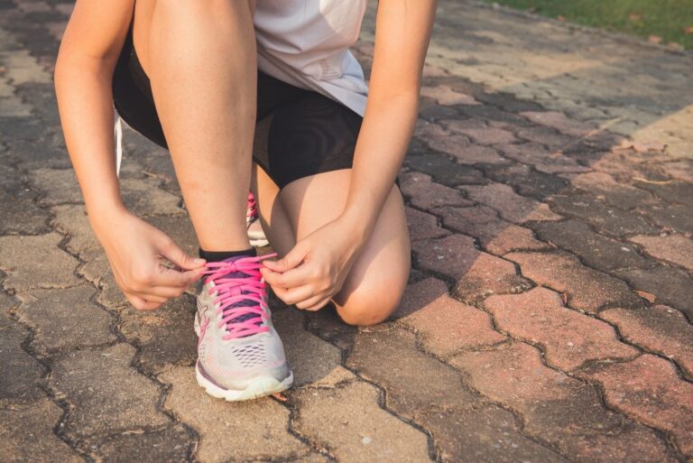 A jogger kneeling and fixing her shoe laces